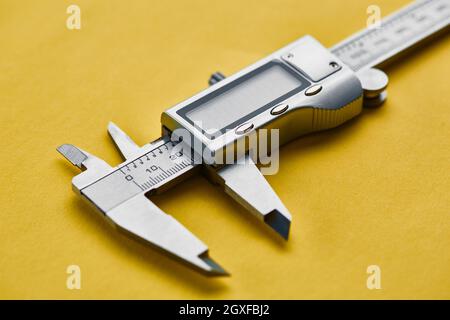 Electronic vernier caliper, yellow background, nobody. Professional measuring instrument, carpenter equipment, measuring tools Stock Photo