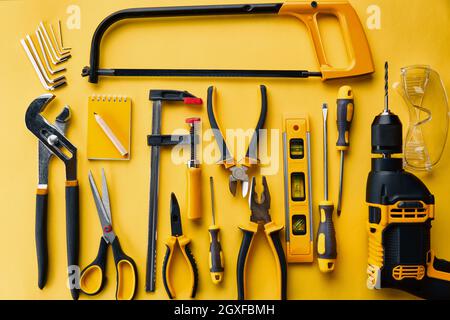 Professional workshop instrument, top view, yellow background, nobody. Carpenter tools, builder equipment, screwdriver and piles, hacksaw and level, s Stock Photo