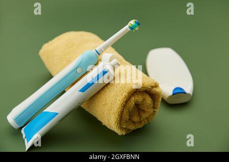 Oral care products, toothbrush, toothpaste and dental floss on towel, green background, nobody. Morning healthcare procedures concept Stock Photo