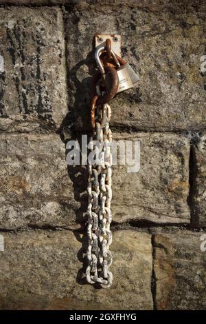 Padlocks and chain hanging on stone wall. Stock Photo