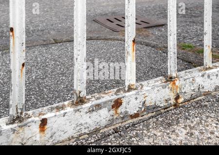 Rusty white gate on gray street background. Stock Photo