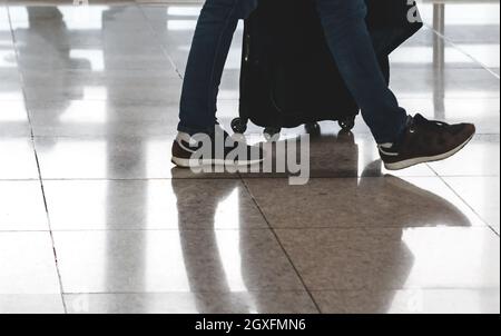 Traveler pulling suitcase in modern airport terminal. Travel and transportation concept Stock Photo