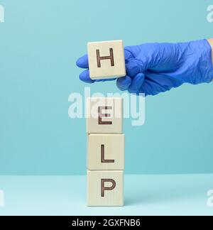 inscription help on wooden cubes and a hand in a blue medical glove. First aid concept, answering questions Stock Photo