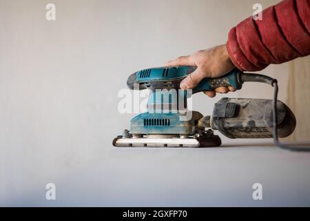 Man sanding wood plank using electric sand machine. Stock Photo