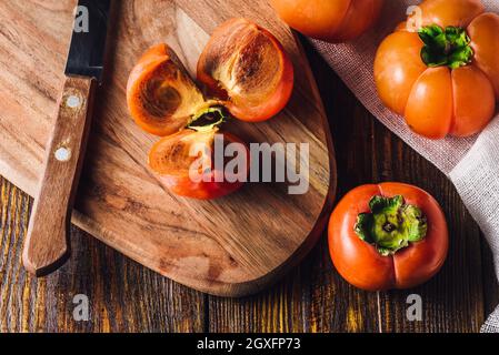 Persimmon Slices on Cutting Board with Kitchen Knife and Persimmons Stock Photo
