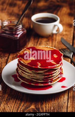 Stack of pancakes with berry fruit marmalade on plate over wooden surface Stock Photo