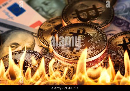 Close up heap of golden bitcoin physical coins and paper money banknotes burning in fire flames, as symbol of economy crisis, decline and market crash Stock Photo
