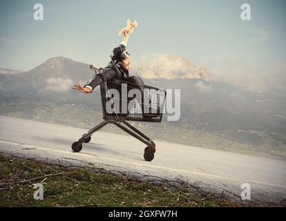 Crazy businessman like a child plays with a wood plane toy on a shopping cart Stock Photo