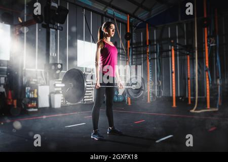 Determined athletic girl works out at the gym with a barbell Stock Photo