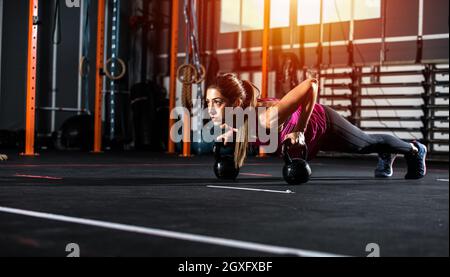 Determined athletic girl works out at the gym with a kettlebell Stock Photo
