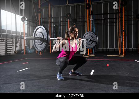 Determined athletic girl works out at the gym with a barbell Stock Photo