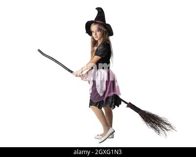 Halloween party witch girl on broom isolated on white background, adorable cute young kid acting to be witch in studio Stock Photo