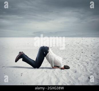 Afraid businessman hides his head under the ground like an ostrich. Fear of crisis concept Stock Photo