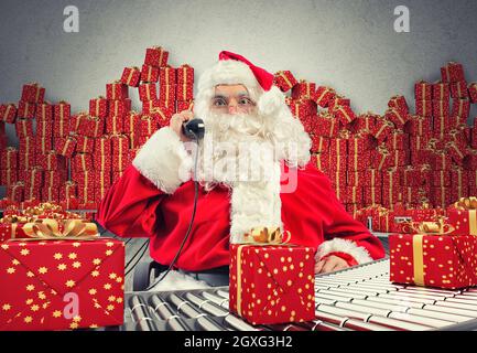 3D Rendering Santa Claus receives requests via telephone sitting in a chair and checking xmas gift boxes and wrapped on conveyor roller Stock Photo