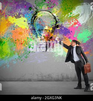 Businessman paints on wall a colorful idea with spray Stock Photo