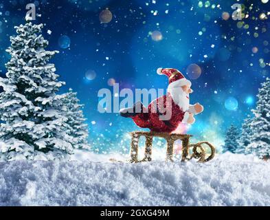 Cute puppet of Santa Claus plays with sleigh on the snow Stock Photo