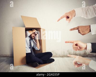 Businessman indicated by colleagues hiding in a cardboard