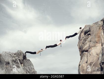 Businessmen working together to form a bridge between two mountains Stock Photo