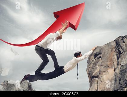 Businessmen working together to form a bridge between two mountains and raising an arrow Stock Photo