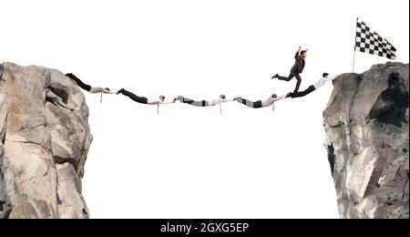 Businessmen working together to form a bridge between two mountains to get to the flag. Achievement business goal concept Stock Photo