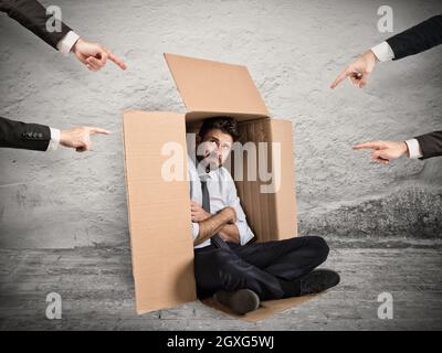 Businessman indicated by colleagues hiding in a cardboard