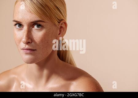 Beauty portrait of a young blond woman. Female with freckles looking straight of a camera. Stock Photo