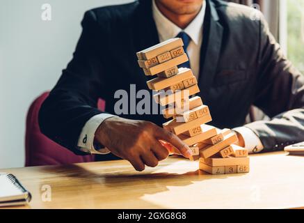 Business man challenge pulling block wood building tower, the block wood has failling on he hand, risk concept Stock Photo