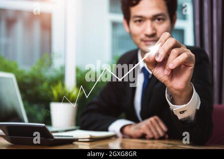 Businessman sitting at office drawing upward arrow up successful finance Stock Photo