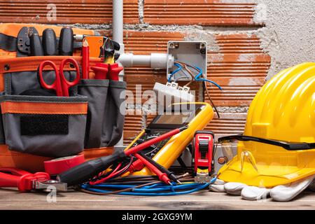 Tool bag, tools and work equipment for electrician technician on a wooden workbench. Construction industry. Stock Photo