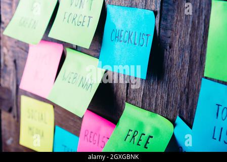 Colorful sticky notes on wooden board reminder. Free webinar checklist social media register written sticker on pineboard. Check list and to do list r Stock Photo