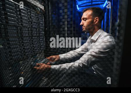Professional European network engineer operating in server room Stock Photo