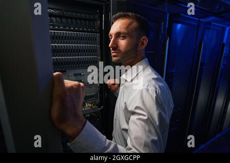 Bearded busy man technician finding and troubleshooting computer server in room indoors Stock Photo