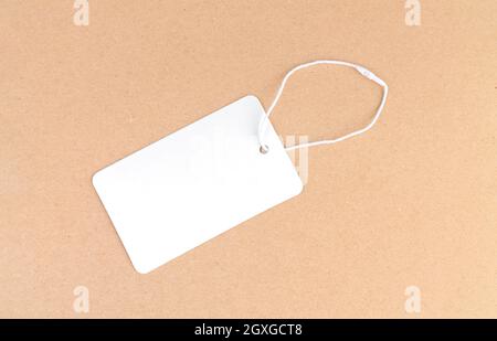 One blank white paper cloth labels or price tags on brown background Stock Photo