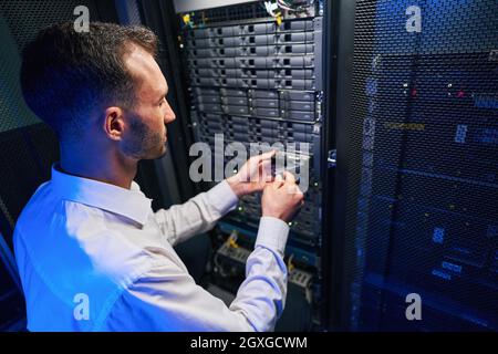 Busy maintenance administrator disassembling and repairing computer server in room indoors Stock Photo