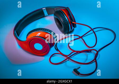 Closeup Photo of a Big Red Headphones on the Table. Stylish Accessory for Dj. Musical Fan. Equipment for a Home Schooling. Photo with Copy Space. Stock Photo