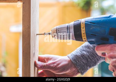 Do it yourself home handyman is using a cordless screwdriver for screwing Stock Photo