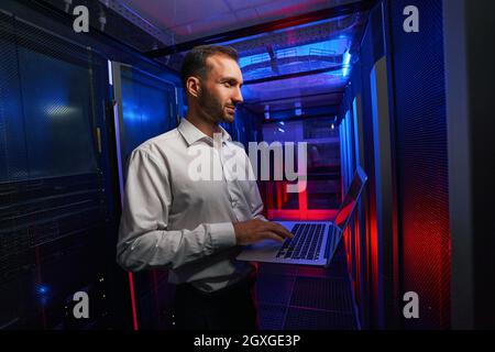 Bearded focused programmer finding and troubleshooting computer server in tech place Stock Photo