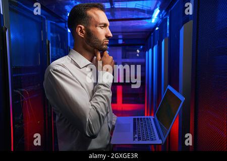 Bearded concentrated professional it specialist examining work of supercomputer in server room Stock Photo