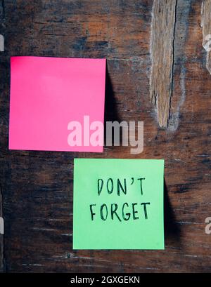 Don't forget written sticker on pineboard. Colorful sticky notes on wooden board background reminder. Don't forget to save the date business concept. Stock Photo