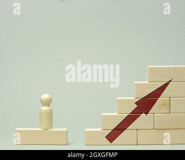 wooden figurine of a man stands on a staircase made of blocks on the first step. The concept of achieving the set goals in business, career growth, st Stock Photo