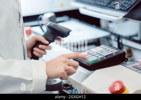 Factory worker pressing the OK button on a machine to start production Stock Photo
