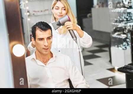 Hairdressing specialist blow-drying man hair with hairdryer Stock Photo