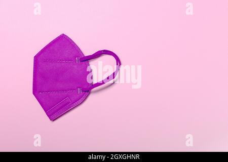 Pink KN95 or N95 FFP2 mask for protection and corona virus on pastel pink background. Anti pollution concept. copy space, from above. Stock Photo
