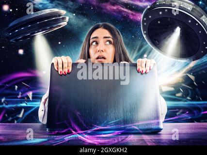 Girl works on the computer surrounded by UFOs. Concept of espionage and security Stock Photo