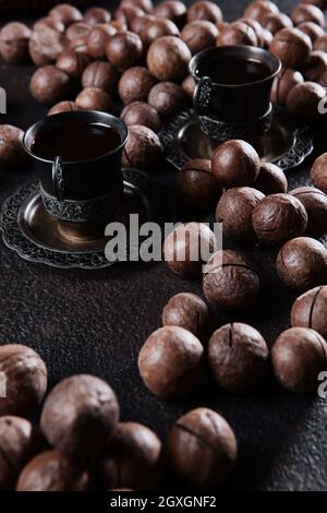 A large number of macadamia nuts are scattered on black background. Whole macadamia nuts. Natural protein and antioxidant. Vertical photo. Stock Photo