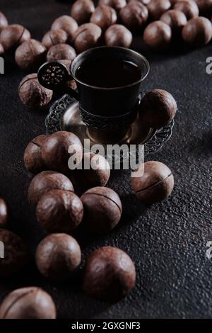 A large number of macadamia nuts are scattered on black background. Whole macadamia nuts. Natural protein and antioxidant. Vertical photo.Top view. Stock Photo