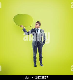Businessman has something to say in a speech bubble on green background Stock Photo