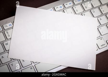 white sheet of paper on computer keyboard as design element, placeholder or space for own graphic elements Stock Photo