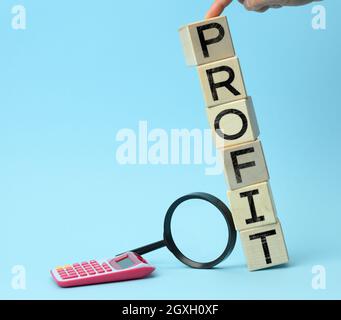 wooden cubes with the inscription benefit, calculator and magnifier on a blue background. The concept of maximum benefits from the deal, the best offe Stock Photo