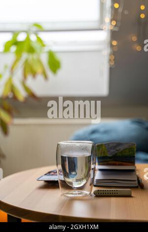Glass cup of hot water on wooden table with watercolor drawing in paper notebook Stock Photo